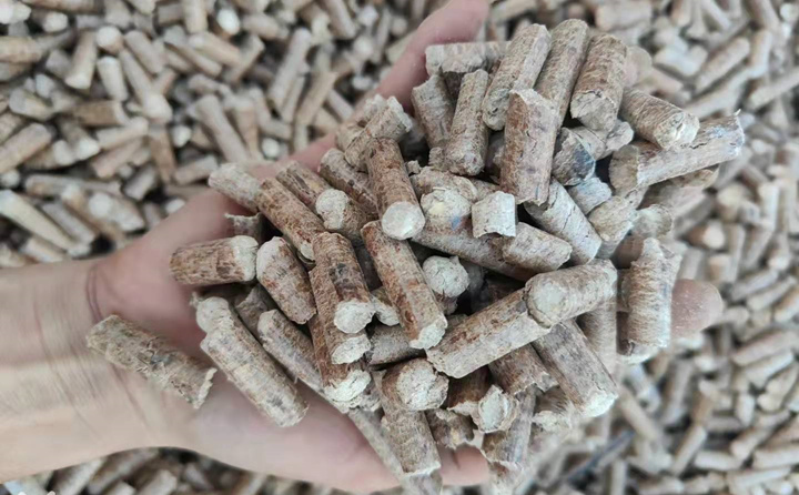 將樹(shù)枝和秸稈粉碎混合后，倒入木屑顆粒機(jī)器中，一截截寸把長(zhǎng)、如粉筆粗的光滑圓柱體順著設(shè)備出口產(chǎn)出.jpg